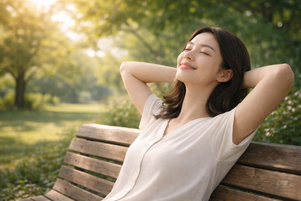 木漏れ日の中でベンチに座り、安心した表情でリラックスする女性の様子