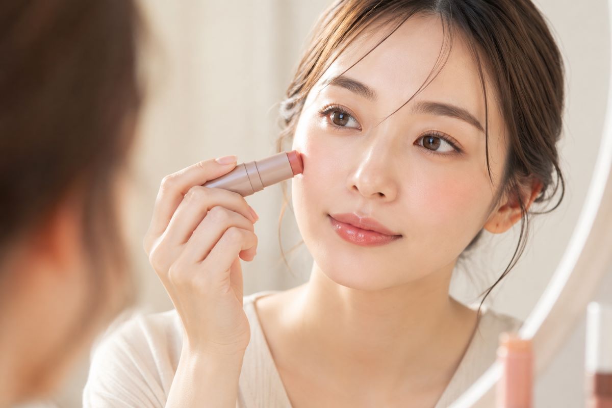 頬にマルチコスメをのせながら自然なワントーンメイクを仕上げる女性の様子