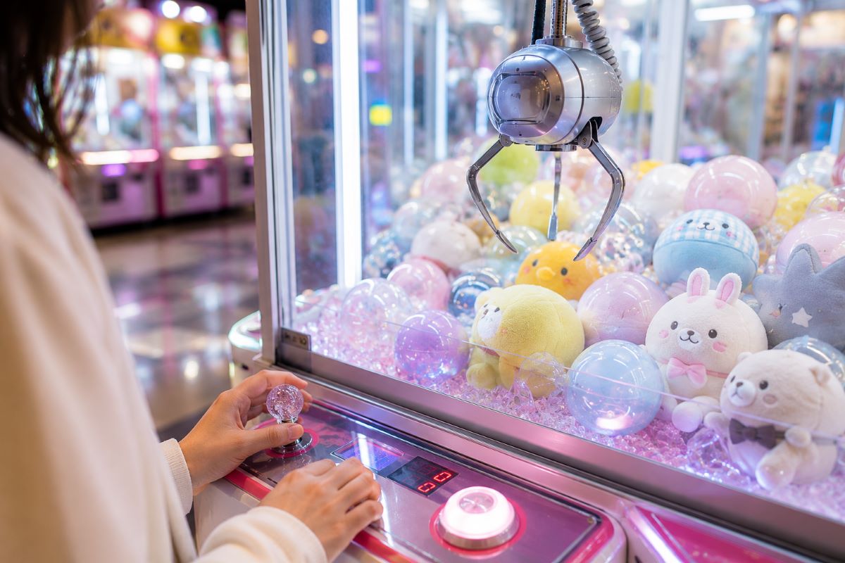 クレーンゲームに挑戦する様子と景品が並ぶ店内を描き、GiGOコラボを楽しむ雰囲気を表現したイメージ